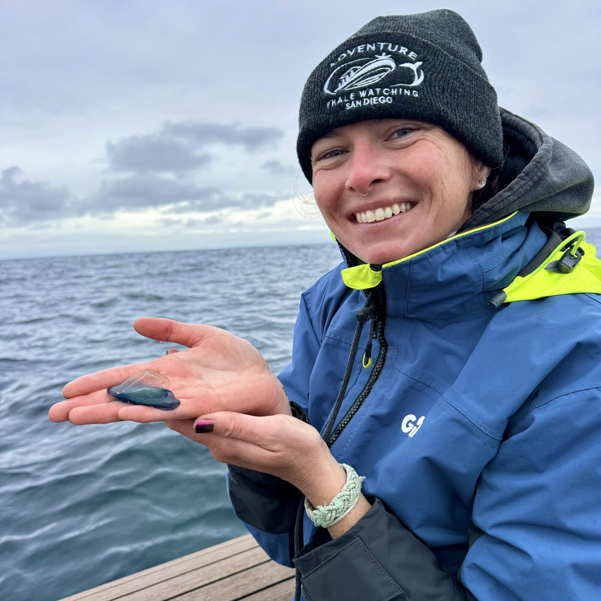 An Adventure Whale Watching naturalist crew member sharing a small sea creature with guests on deck