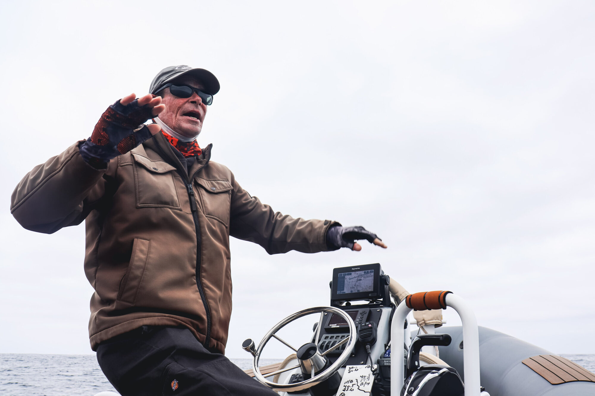 An Adventure Whale Watching captain narrating from the RIB helm, gesturing toward the open ocean